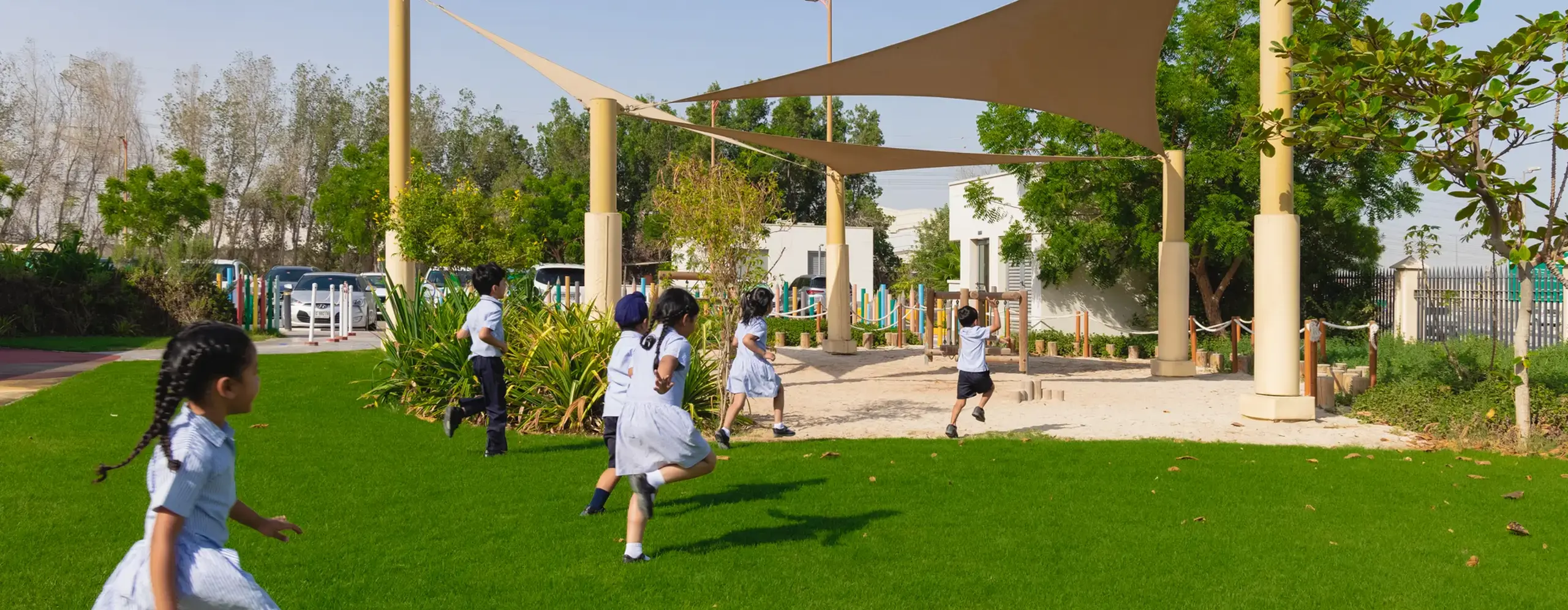 Young students running towards a building from the playground.