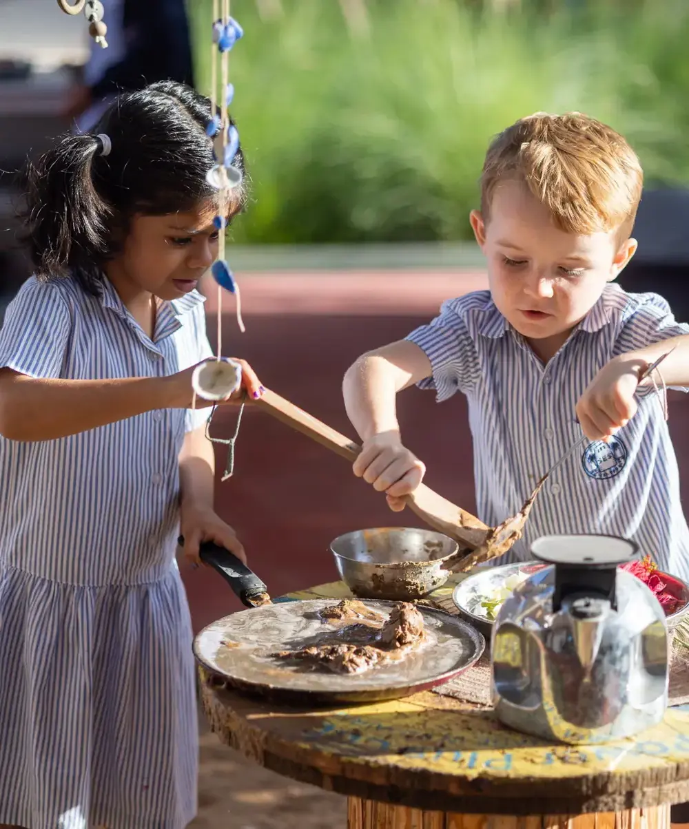 Two primary students experimenting with food outside.