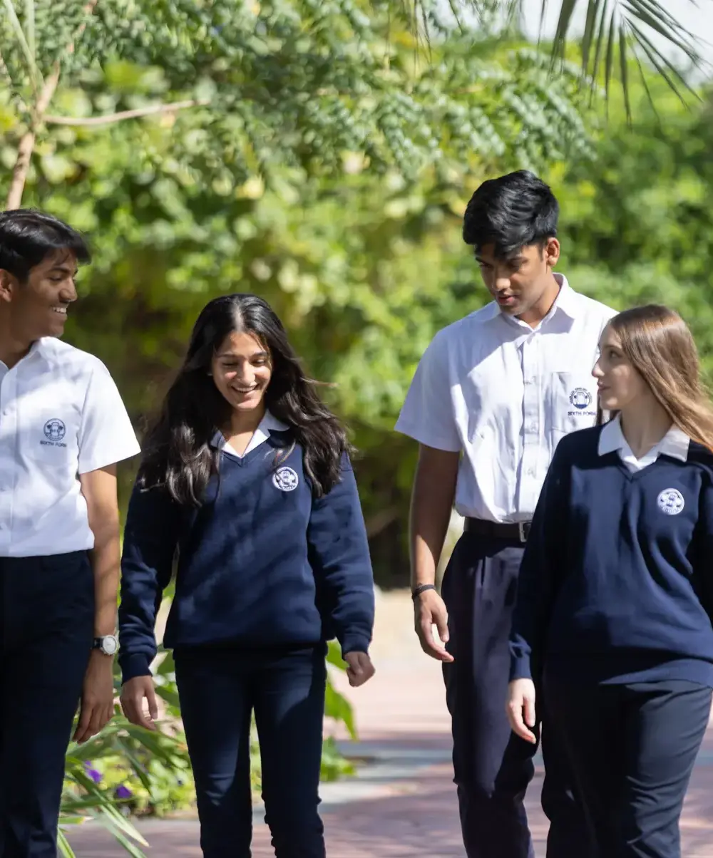 Two head boys and two head girls walking and laughing outside on the campus.