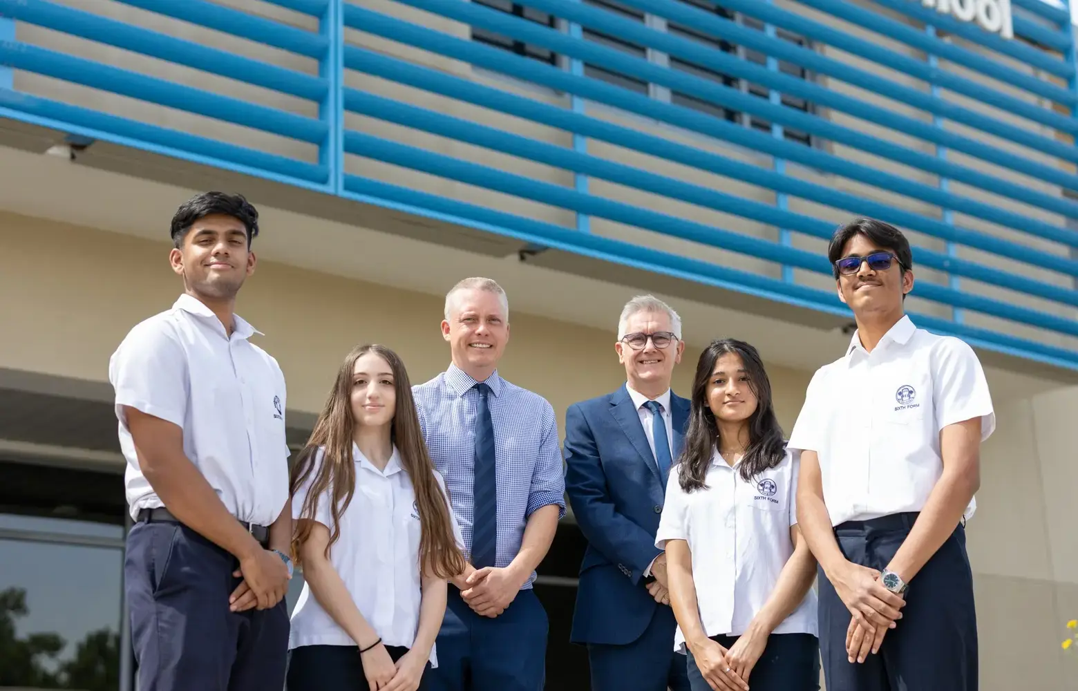 Sharjah's two head boys and two head girls posing in front of building with school leaders.