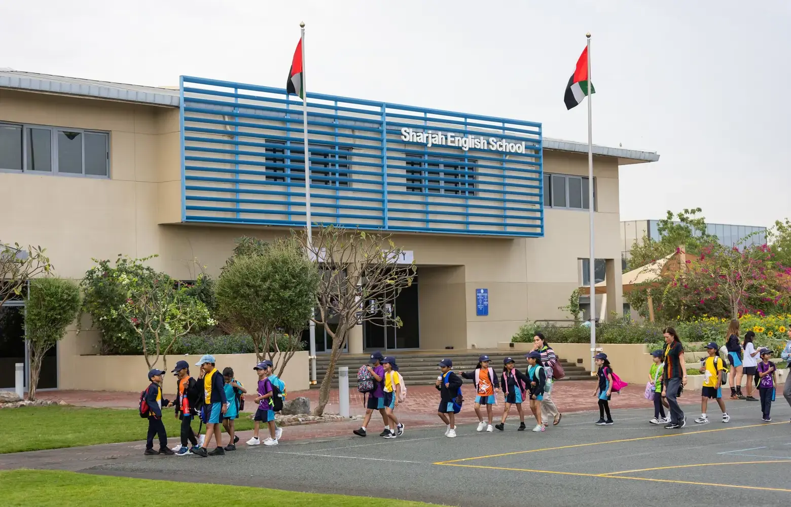 Front of Sharjah English School building with students walking outside.