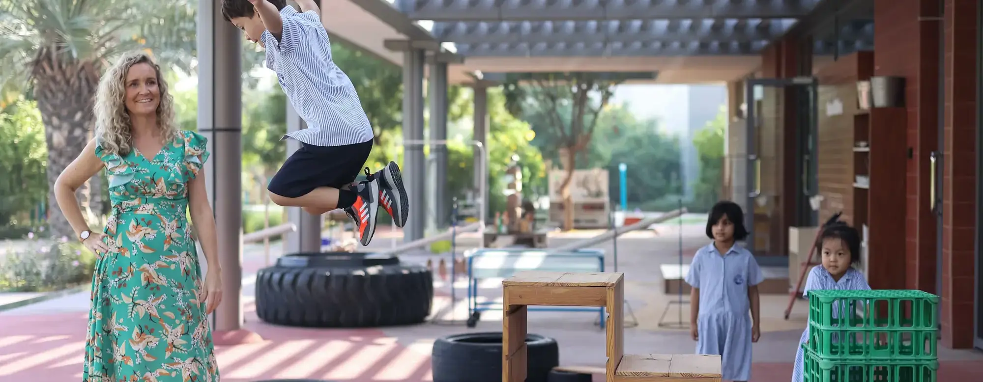 Primary teacher watching student mid-jump.