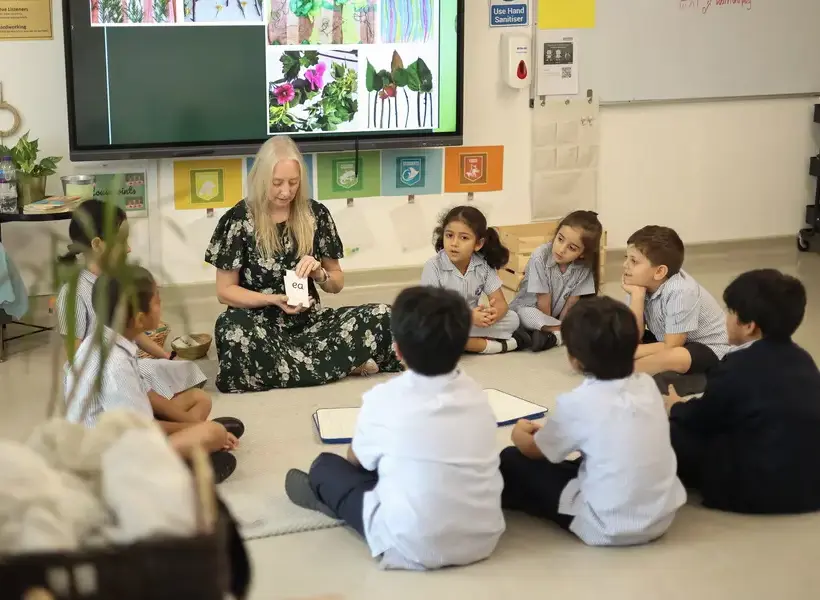 Teacher reading to students sat in a circle.