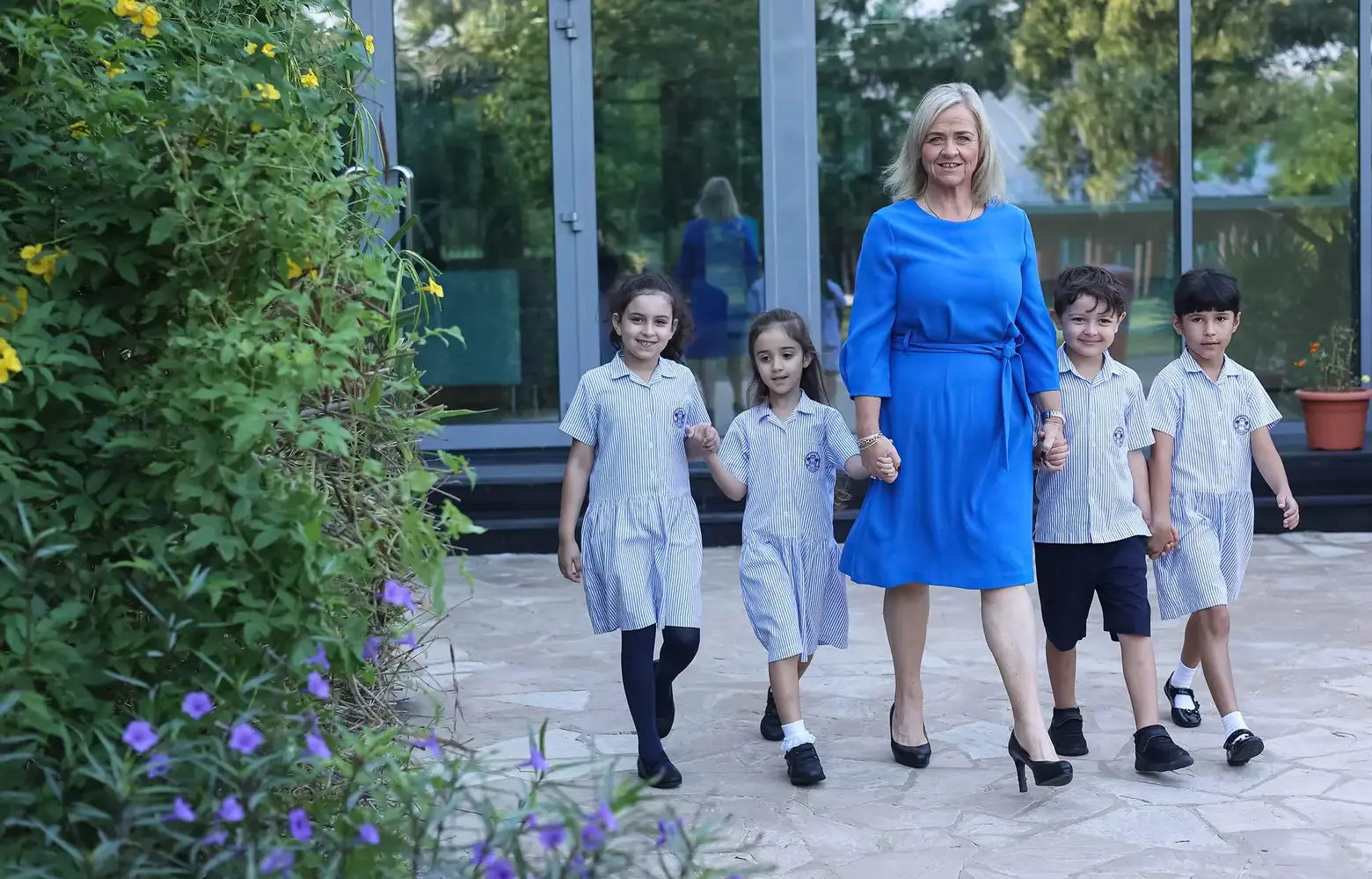 Four young Sharjah students walk with a teacher outside.